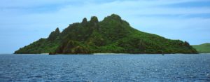 Monu island rises dramatically out of an ink blue Pacific Ocean, Mamanuca Islands, Fiji